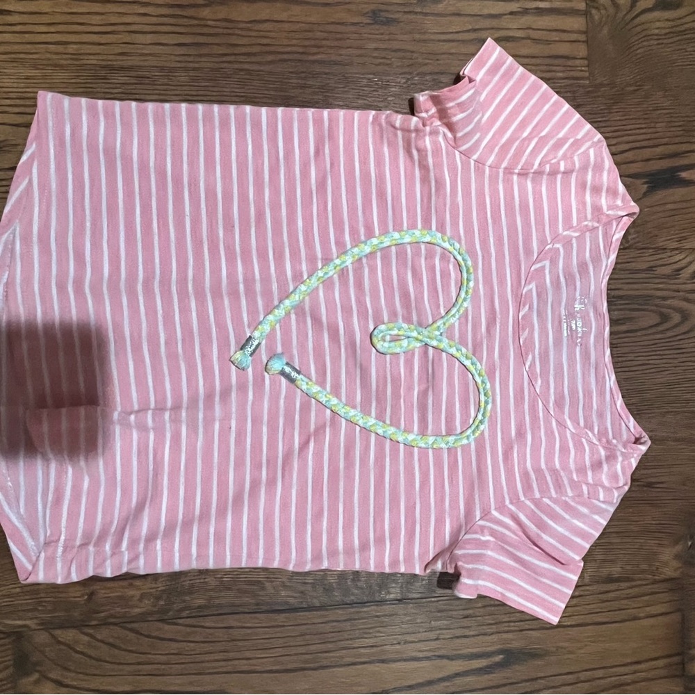 A yellow blue white heart that pops up on top of a pink and white striped shirt